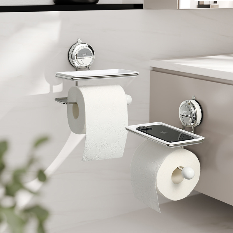 Bathroom setting with toilet paper holder and smartphone stand on a white surface.