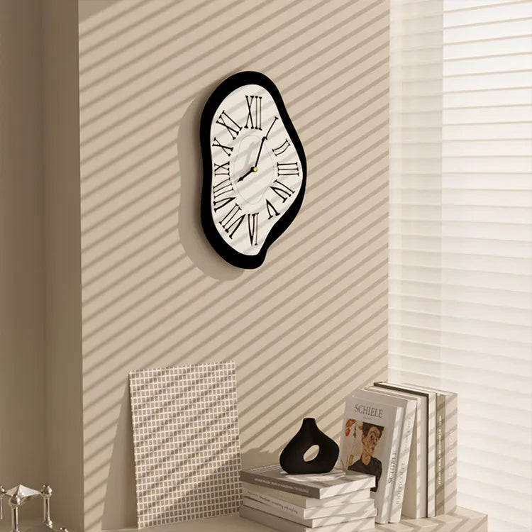Modern wall clock on a textured wall with books and decor items below.