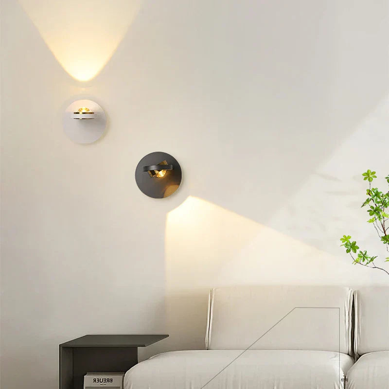 Modern wall sconces on a white wall with a bed and nightstand in the background.