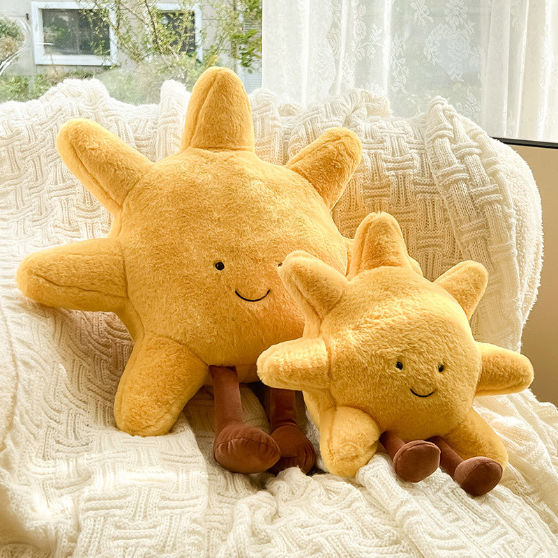 Two plush sun-shaped toys on a textured surface with a window in the background