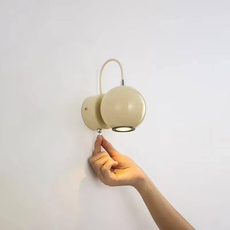 Hand adjusting a wall-mounted light fixture against a plain background