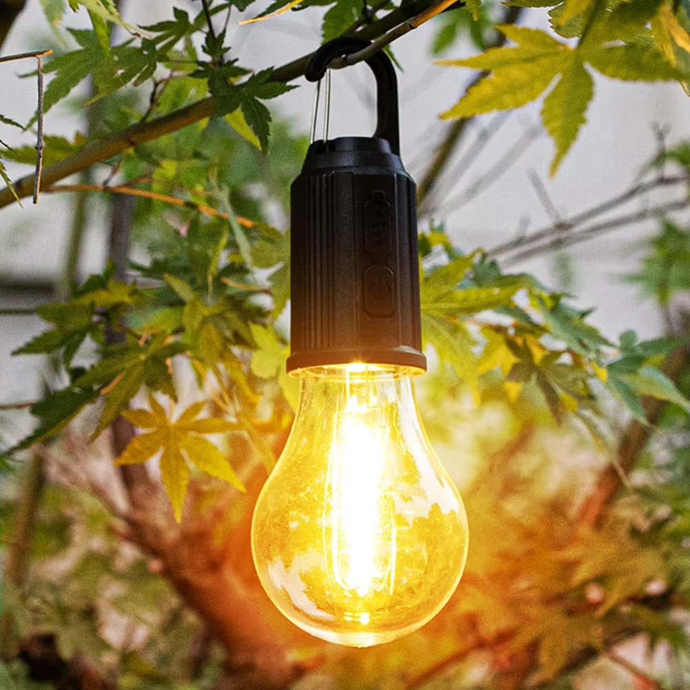 Solar-powered light bulb hanging among green leaves