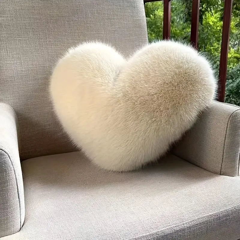 Heart-shaped fluffy white pillow on a gray chair with a blurred green outdoor background