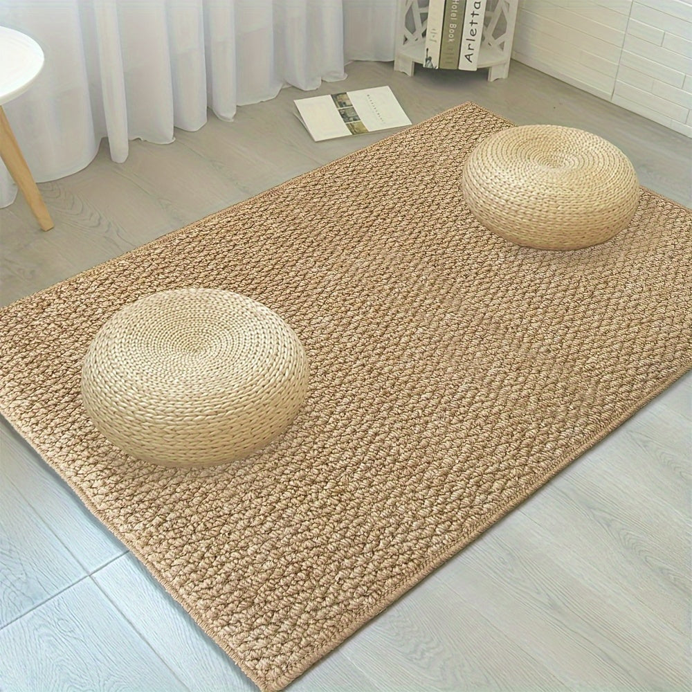 Beige woven rug with two round straw pillows on a light wooden floor.