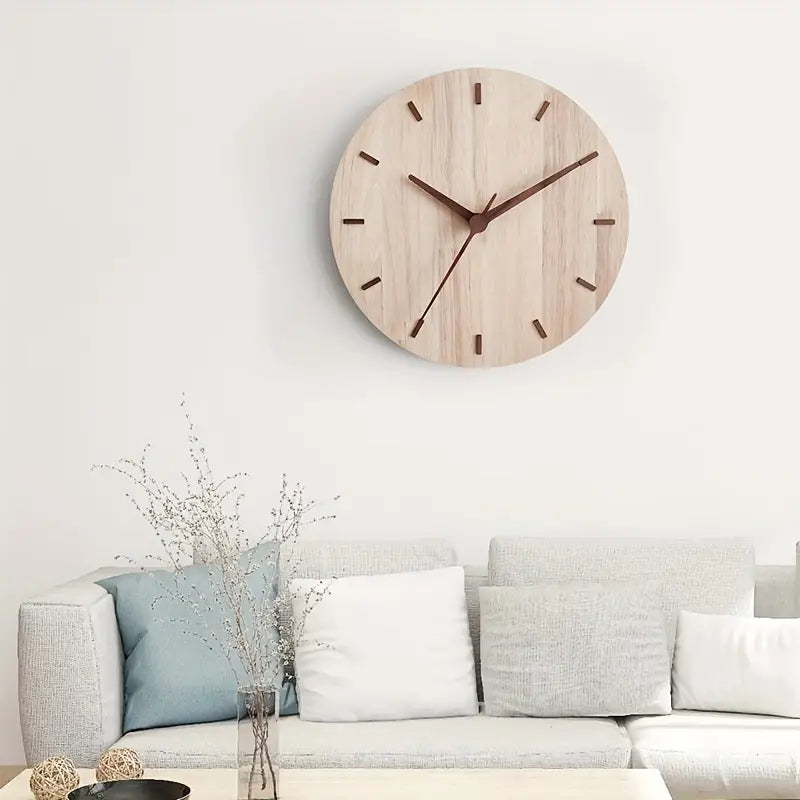 Wooden wall clock on a white wall above a sofa with decorative pillows.