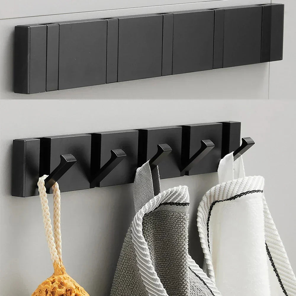 Black wall-mounted hook rack with hooks holding towels on a light gray wall.