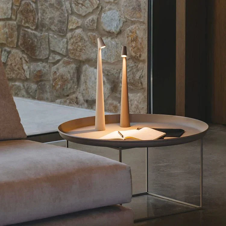Round coffee table with two tall candle holders against a stone wall.