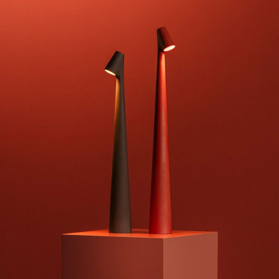 Two modern table lamps, one black and one red, on a red background.