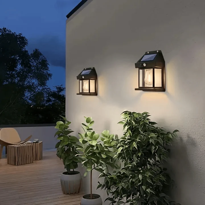 Solar-powered outdoor wall lights on a building exterior with plants and furniture.
