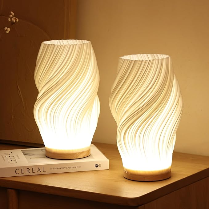 Two illuminated table lamps with wavy design on a wooden surface.