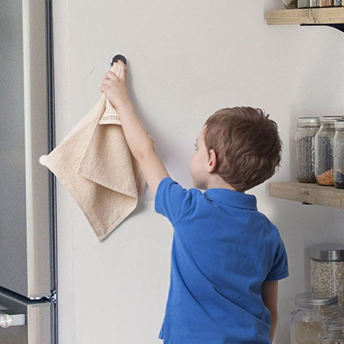 Child in a blue shirt cleaning a refrigerator with a beige towel.