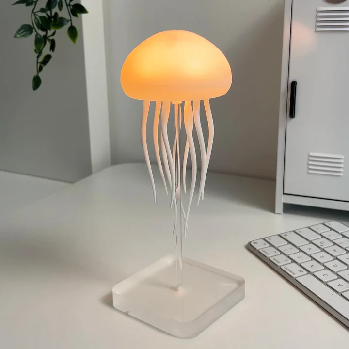 Jellyfish-shaped lamp on a desk with a keyboard and plant in the background