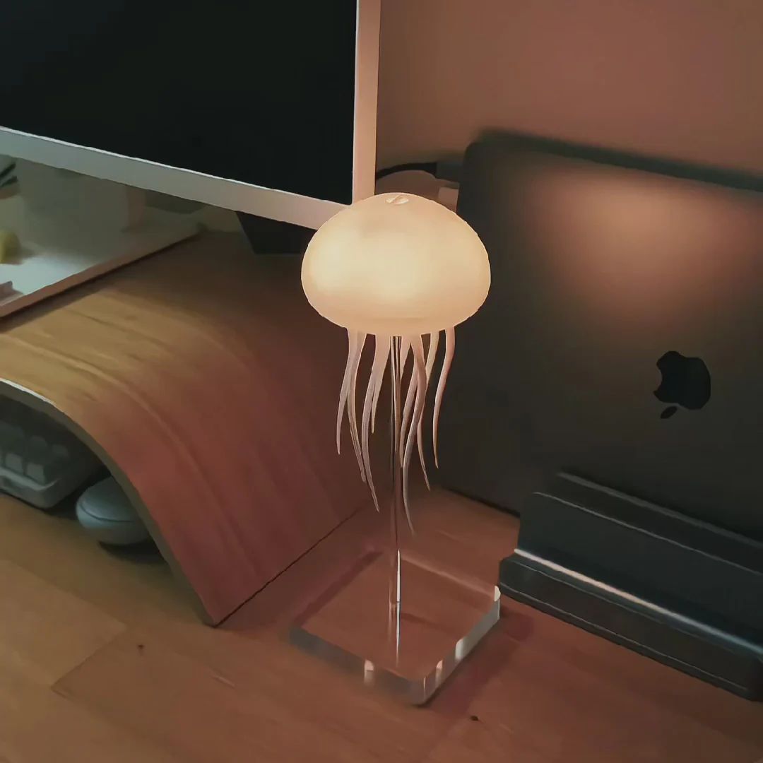 Jellyfish-shaped lamp on a desk next to a computer monitor and keyboard