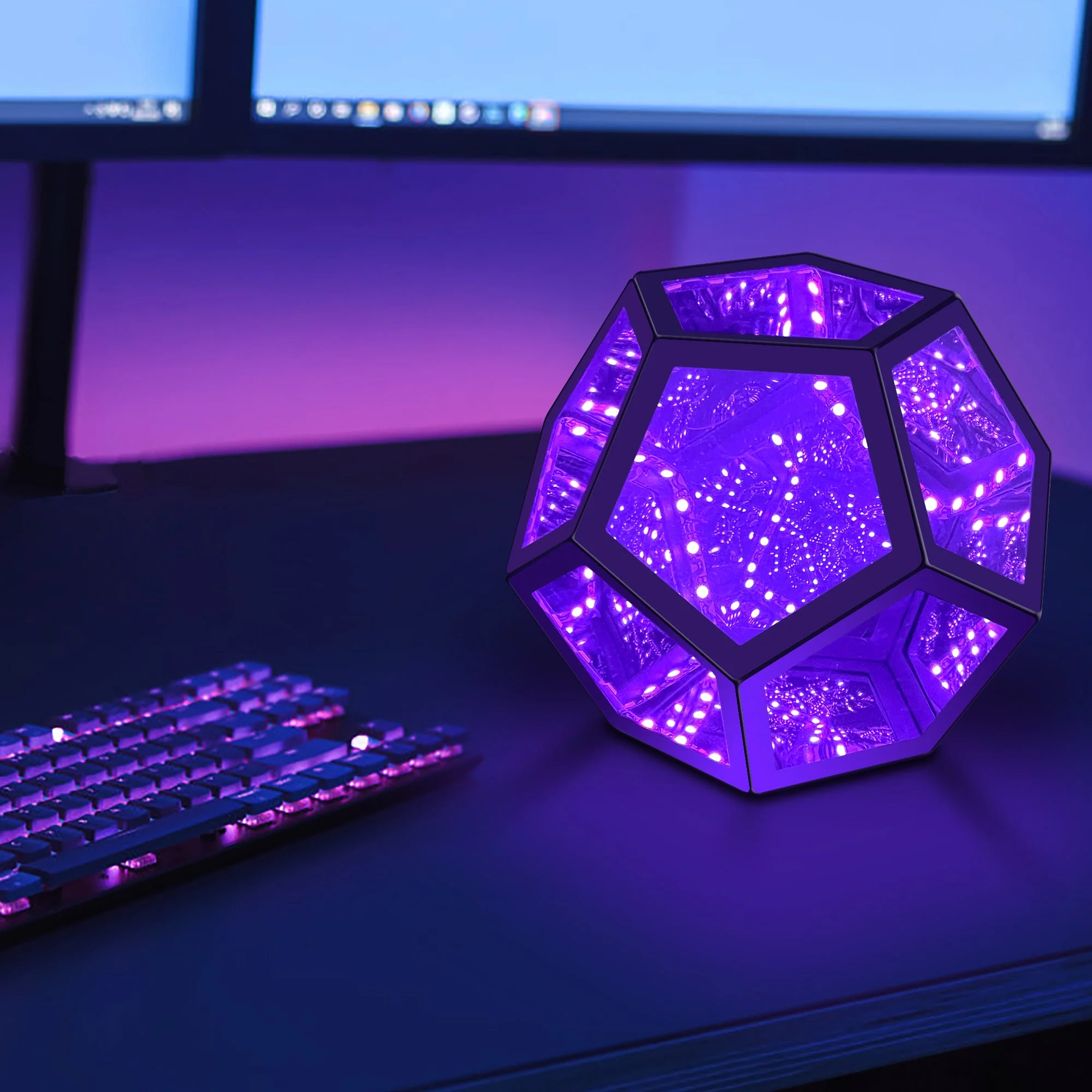 Geometric purple light on a desk with computer monitors and keyboard in the background
