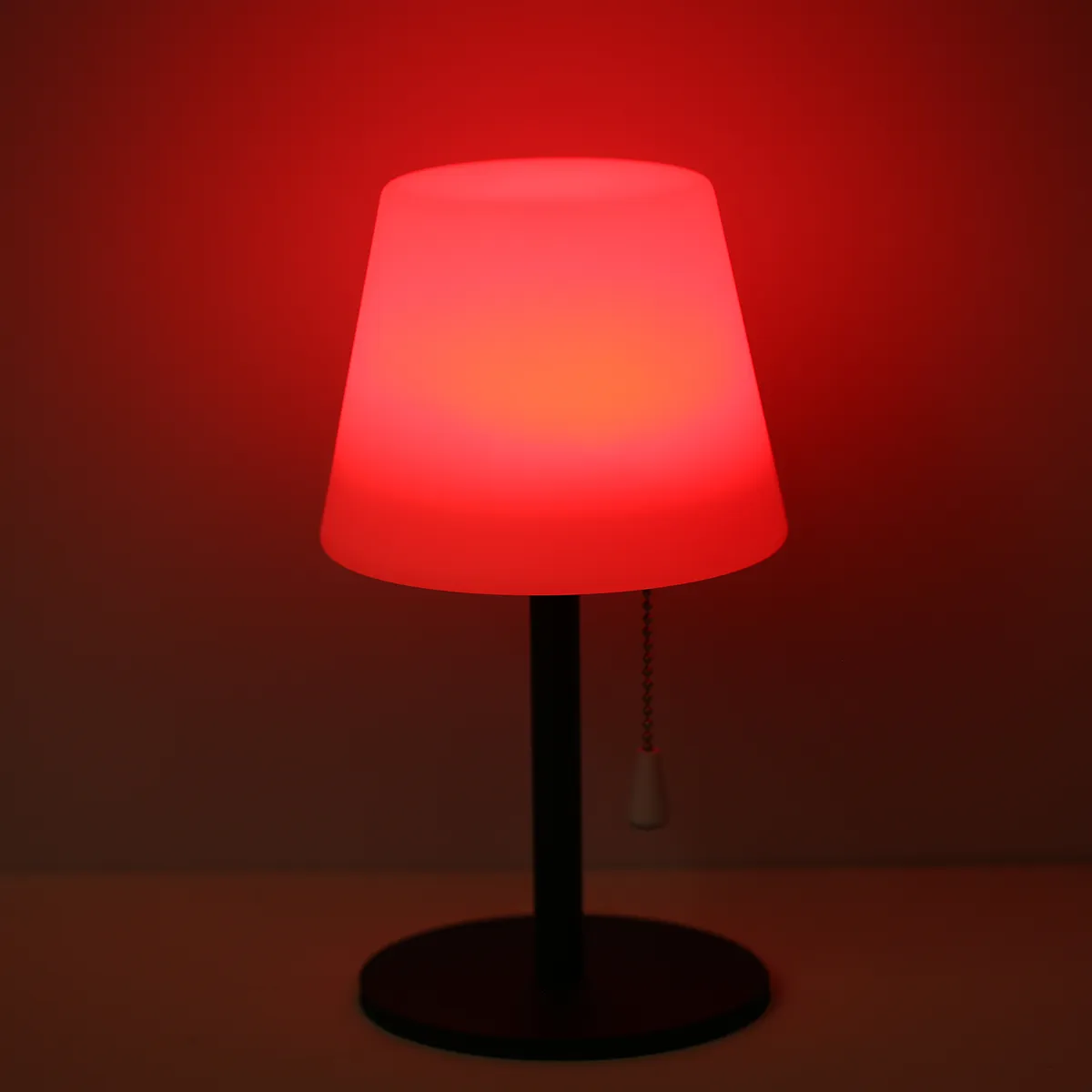 Table lamp with a red gradient shade on a dark background