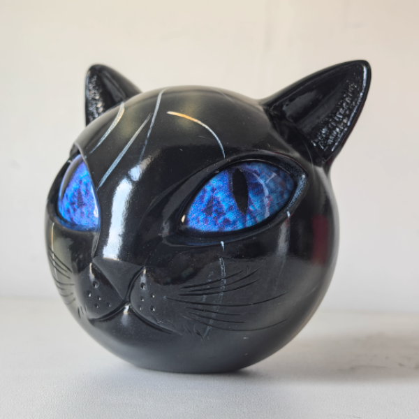 Black cat-shaped object with glowing blue eyes on a white background