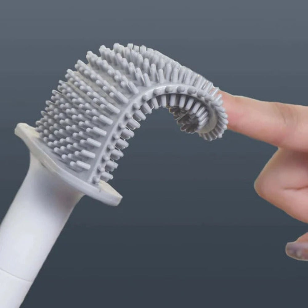 Hand holding a white and gray scrubber with bristles against a dark background