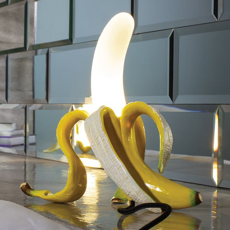Banana-shaped lamp on a reflective surface with a metallic background