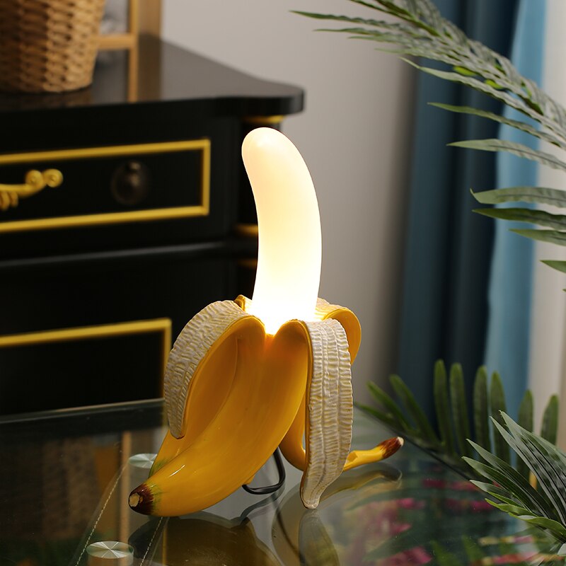 Banana-shaped night light on a reflective surface with a blurred background