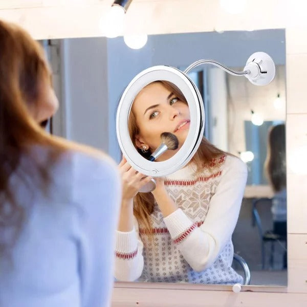 Woman using a magnifying makeup mirror with light in a bathroom setting.