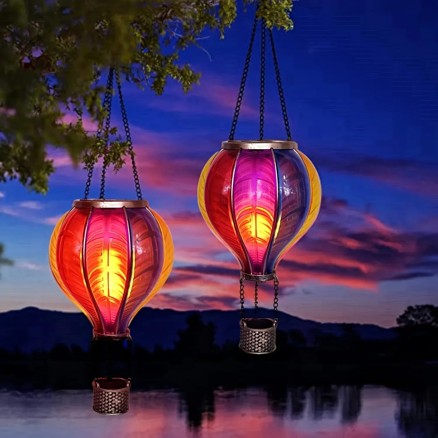 Two colorful hanging lanterns against a sunset sky with mountains and water.