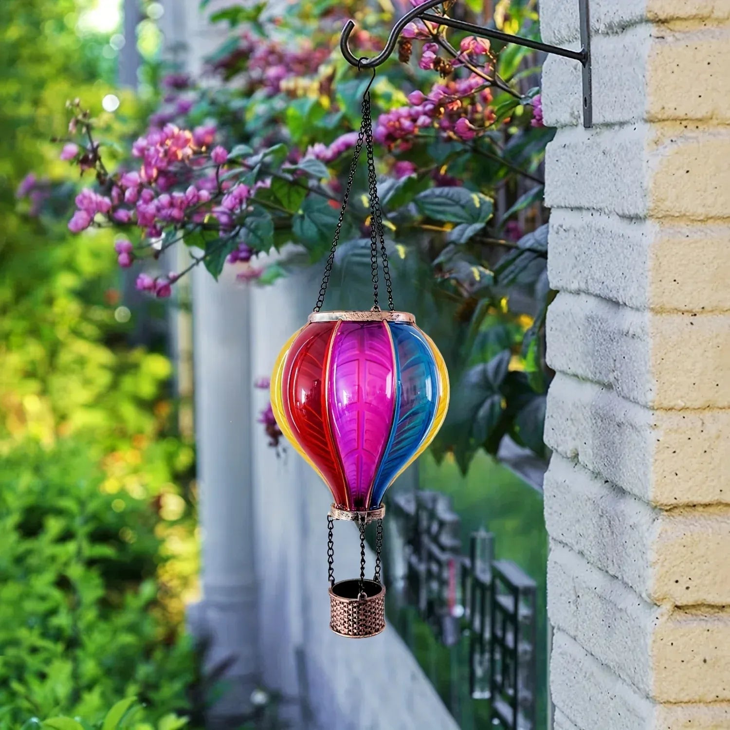 Colorful hot air balloon-shaped hanging lantern against a garden background