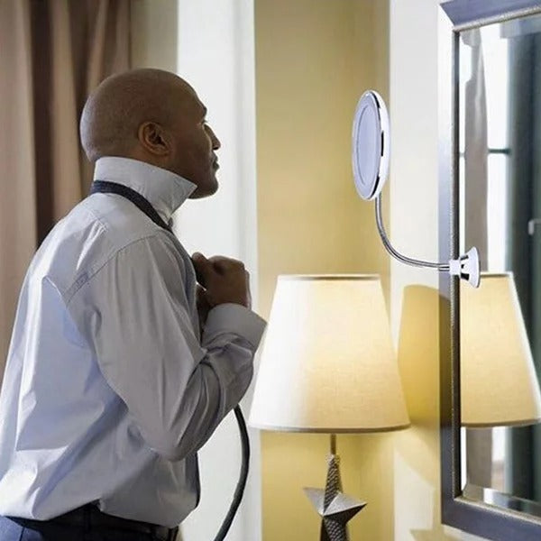 Man adjusting his tie in front of a mirror with a lamp and window in the background