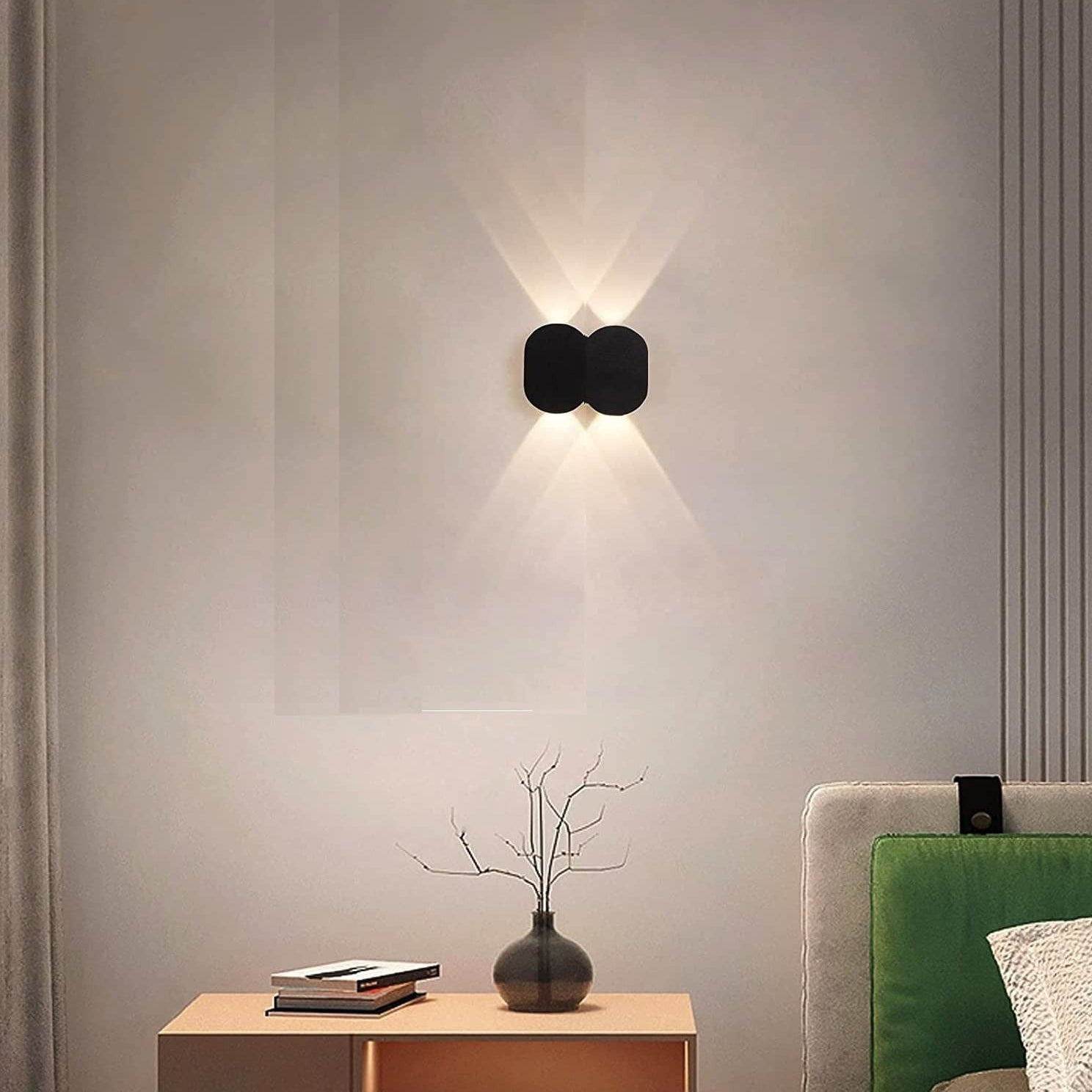 Modern wall lamp on a neutral wall with a side table and green sofa in the foreground.