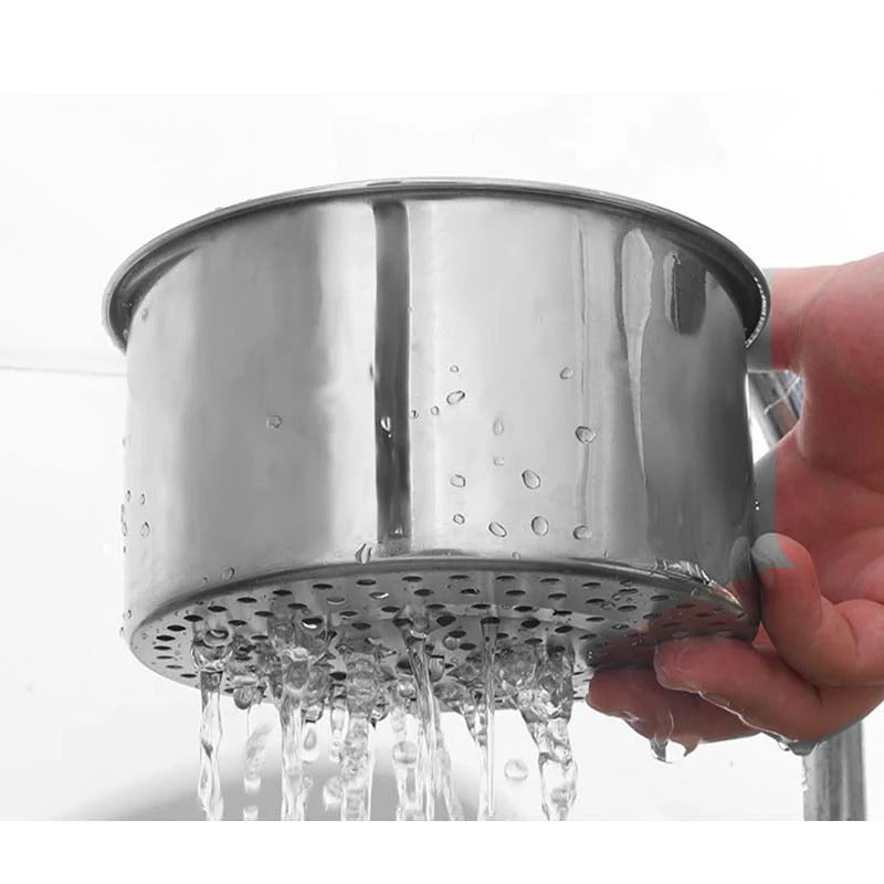 Metal shower head with water flowing, held by a hand against a white background