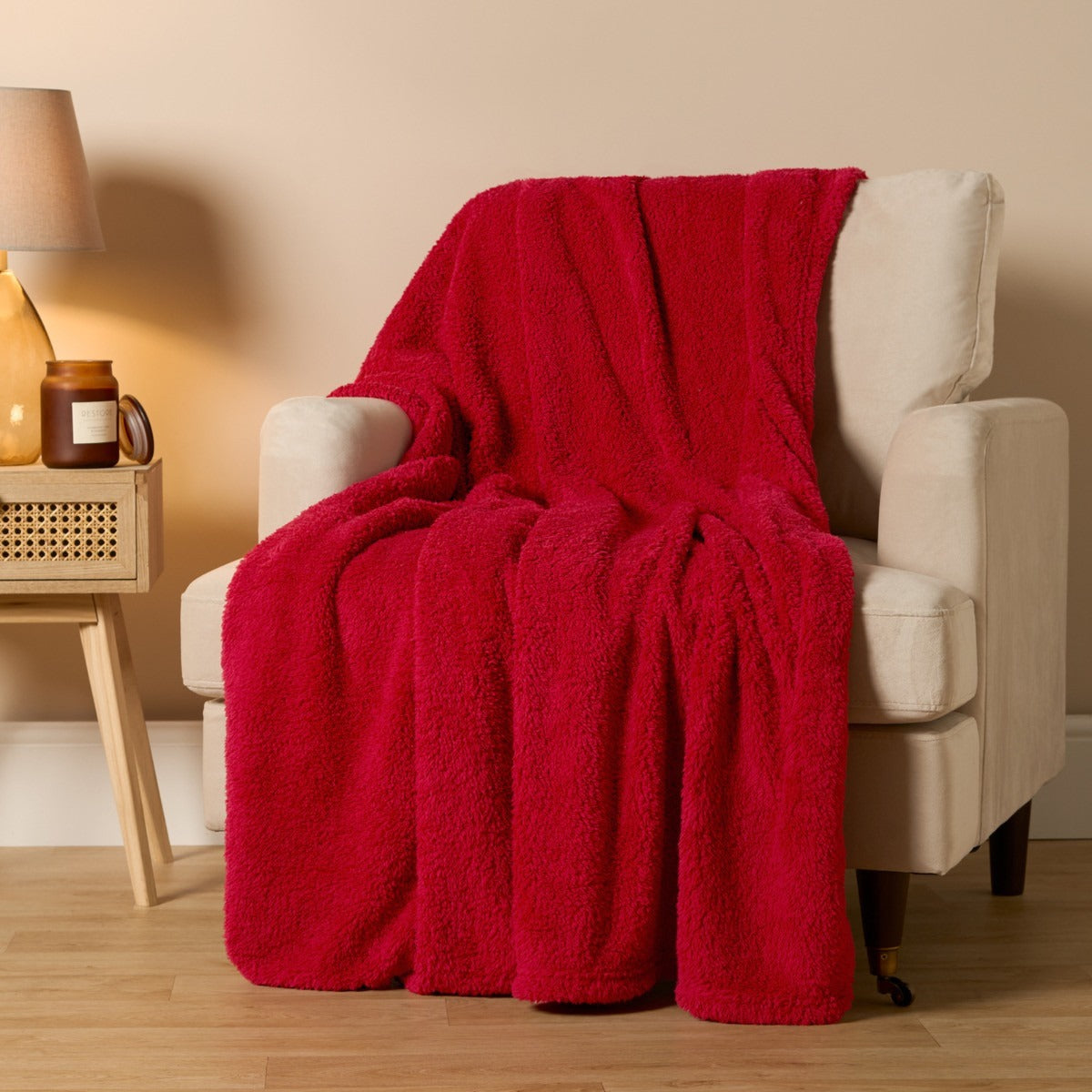 Red blanket draped over a beige armchair in a cozy living room setting.