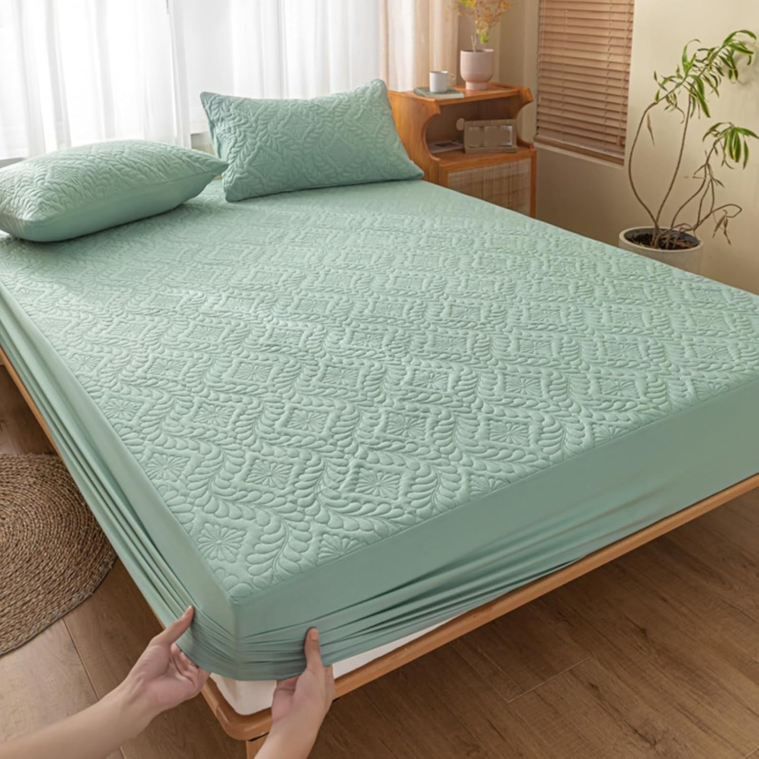 Green mattress cover being held by a person in a bedroom setting.