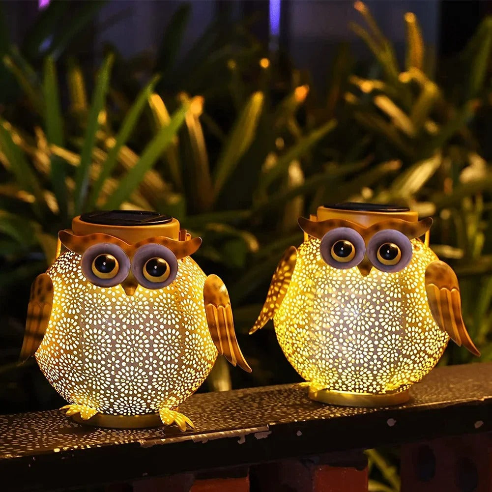 Two owl-shaped solar lights on a surface with plants in the background