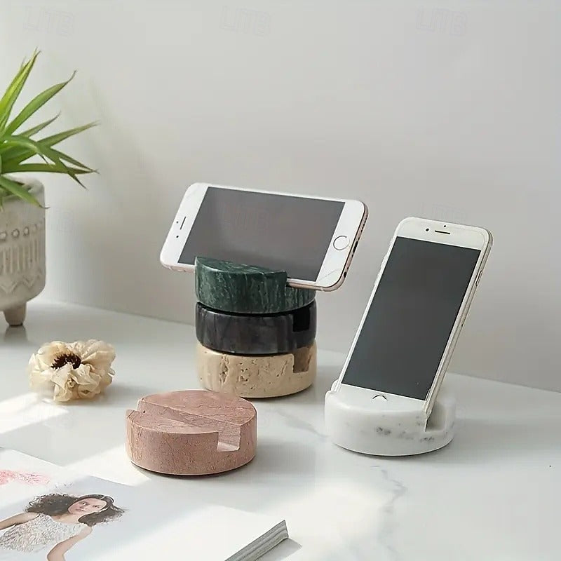 Three phone stands on a desk with smartphones on top, next to a plant and decorative items.