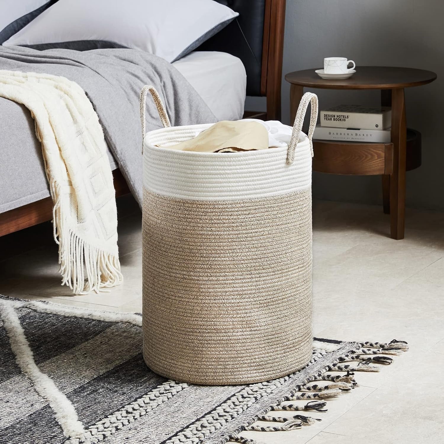 Beige woven laundry basket in a living room setting with a sofa and coffee table.