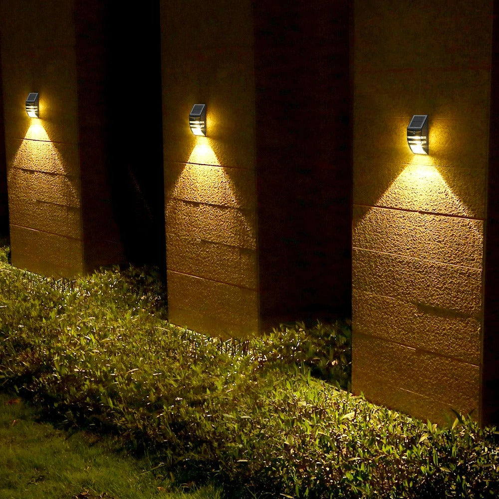 Three outdoor wall lights on a stone wall with grass below