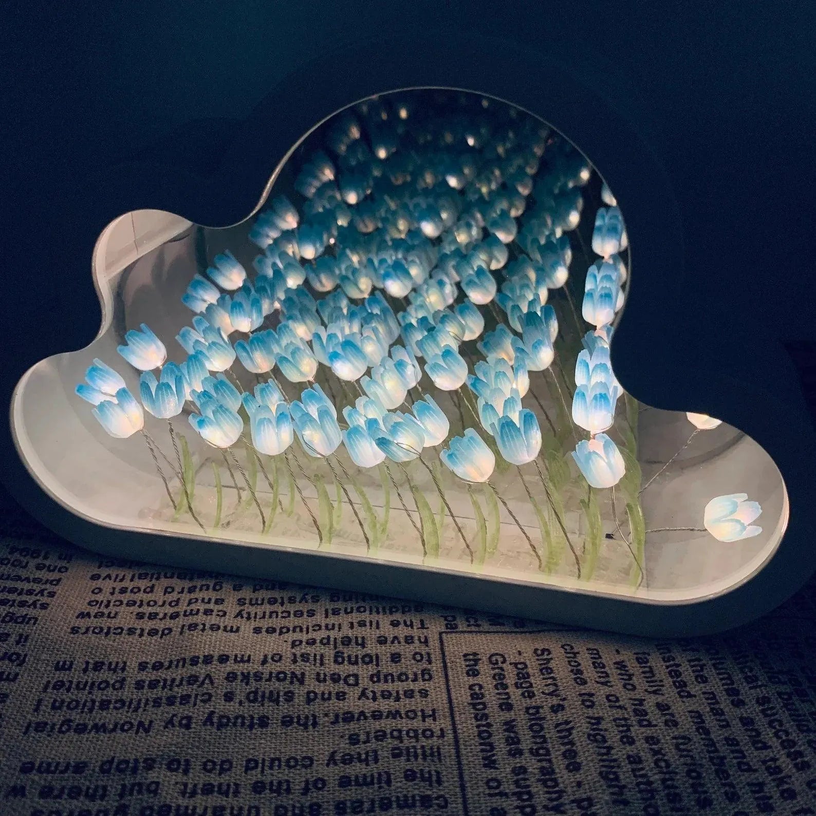 Decorative lamp shaped like a cloud with blue tulips on a dark background