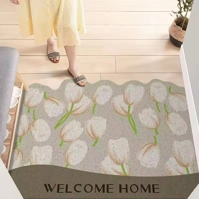 Decorative doormat with tulip pattern and 'Welcome Home' text on a wooden floor.