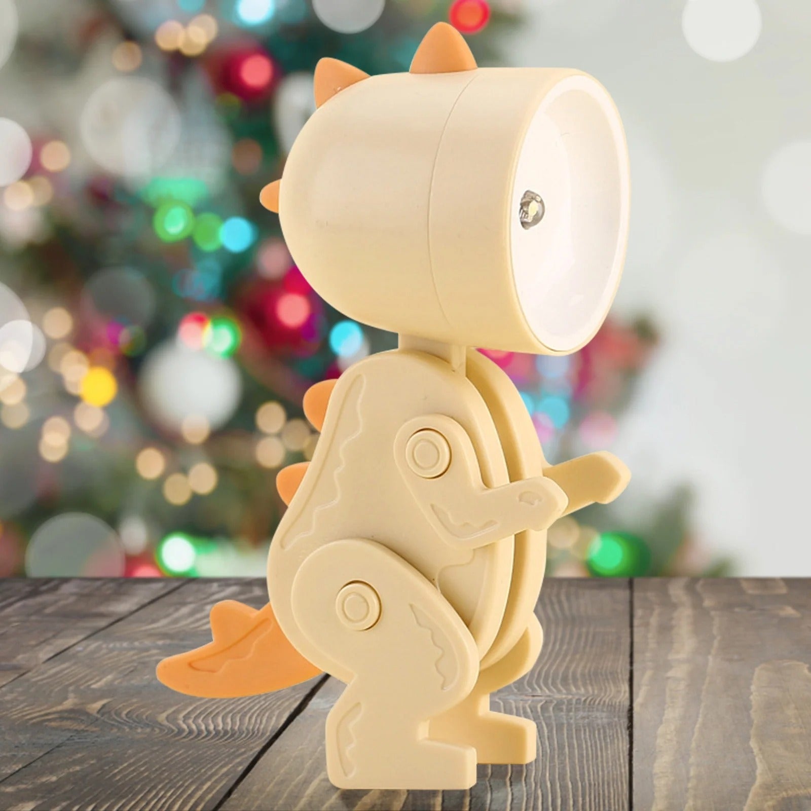 Children's dinosaur lamp on a wooden surface with a blurred festive background