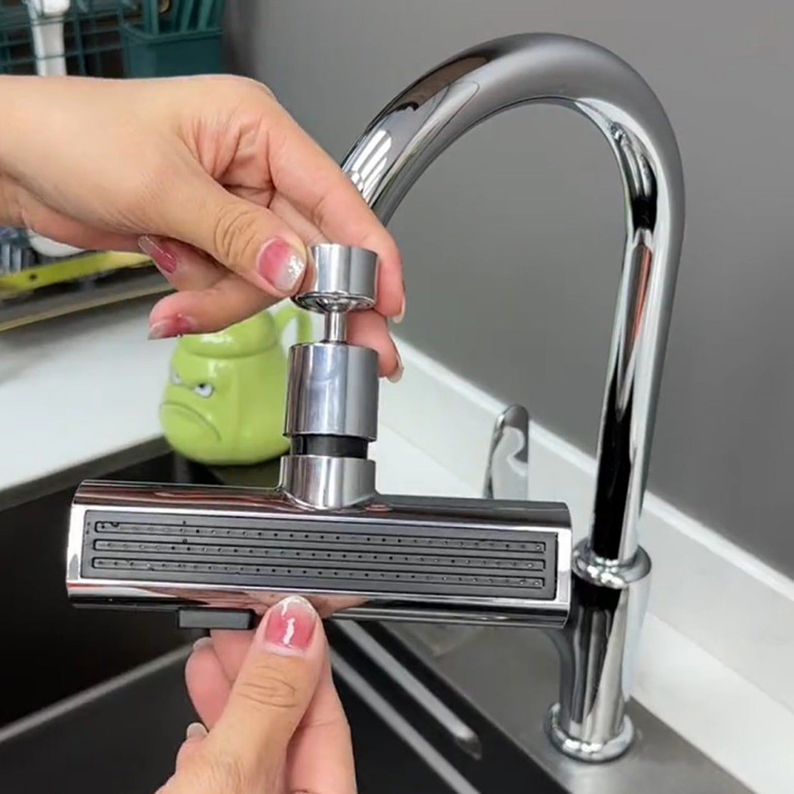 Person holding a kitchen faucet handle in front of a sink