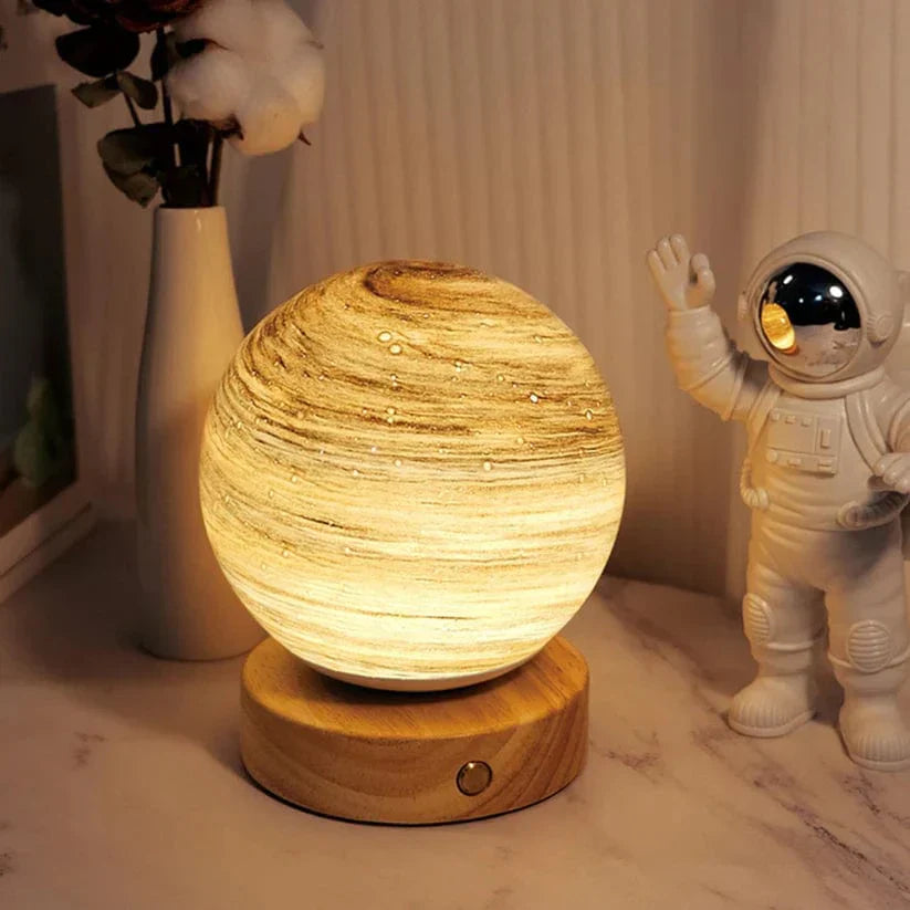 Decorative lamp with wooden base on a surface next to an astronaut figurine and a vase with cotton.