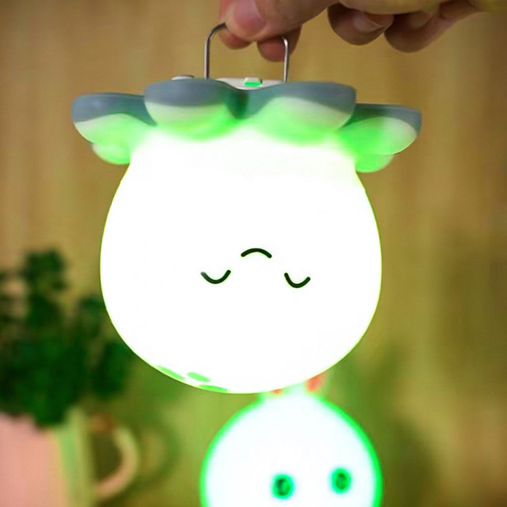 Glowing white lantern with green accents shaped like a cloud, held by a hand against a blurred background.