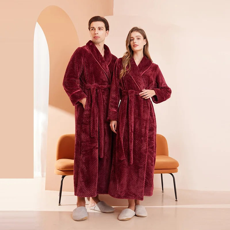 Two people wearing burgundy robes standing in a room with a peach wall and chair.