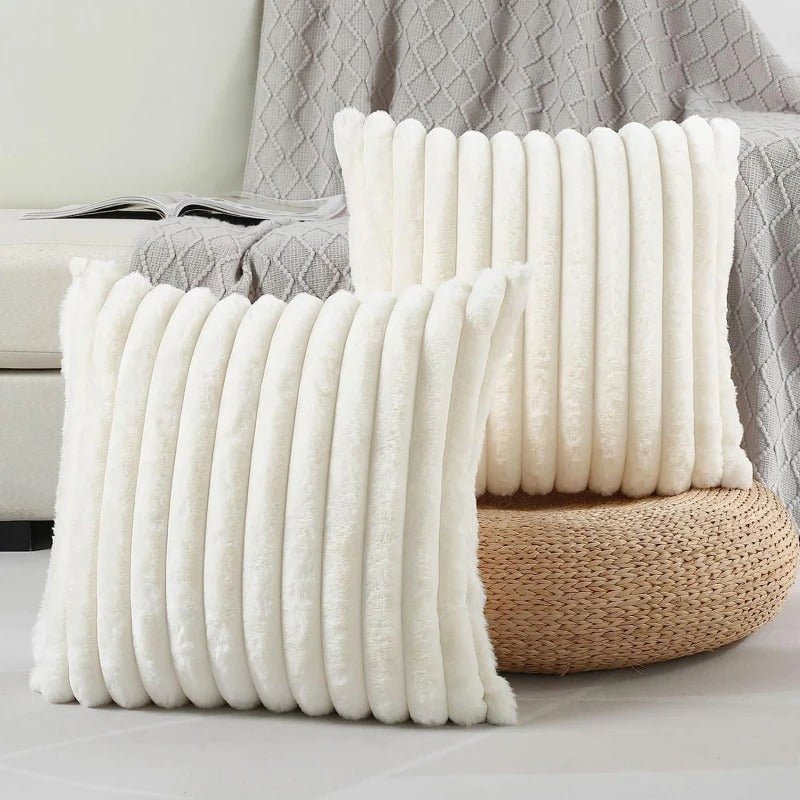Two white textured pillows on a surface with a gray textured blanket in the background.