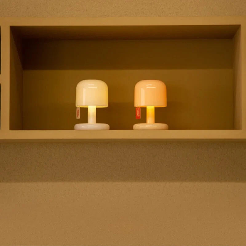 Two small, round lamps with a warm glow on a beige shelf.