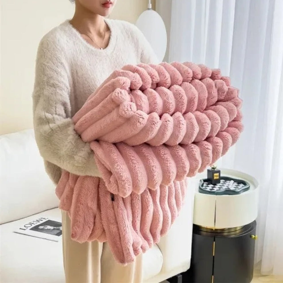 Person holding a large pink textured blanket in a living room setting.