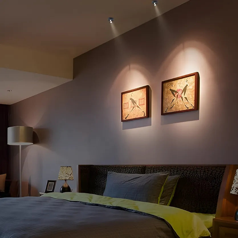 Bedroom with two framed artworks on the wall, a lamp, and a bed with green and blue bedding.