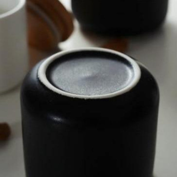 Close-up of a black ceramic container with a lid on a light background