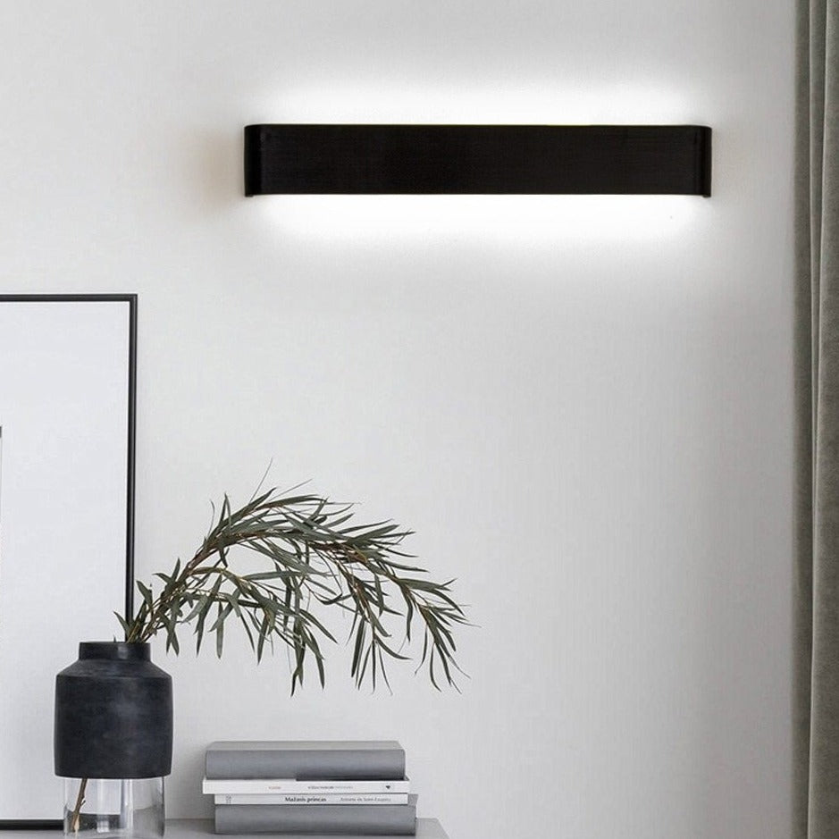 Modern wall-mounted light fixture on a white wall with decor elements.