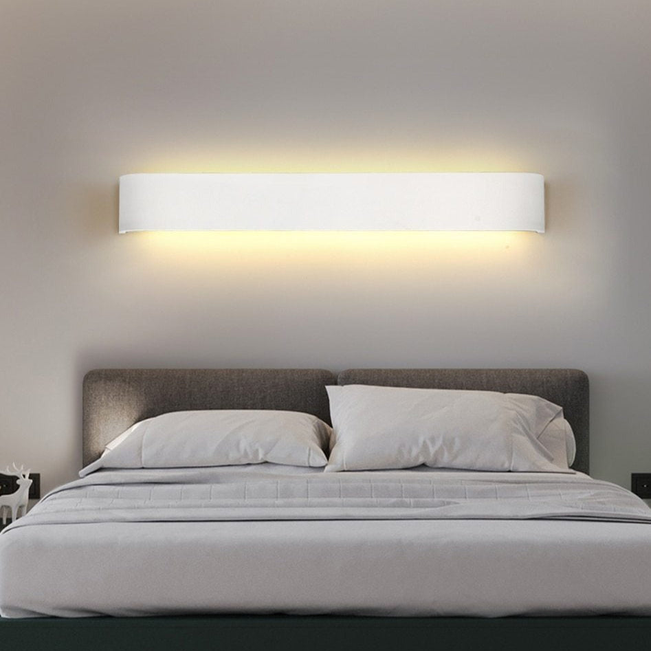 Modern bedroom with a bed and wall-mounted light fixture.