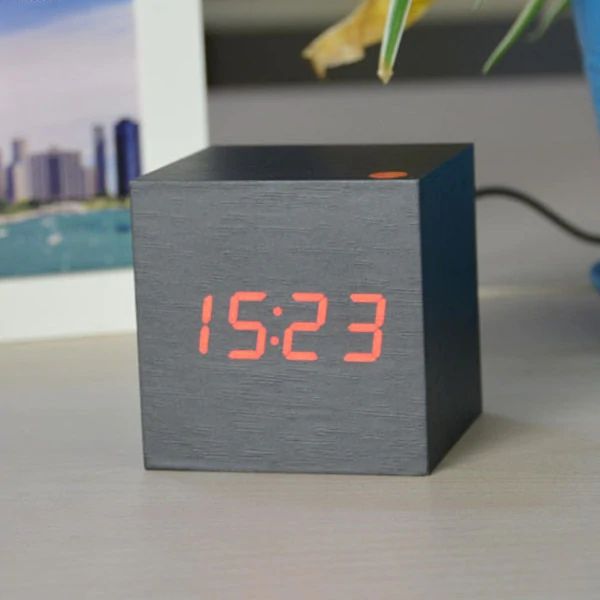 Black digital clock with red LED display on a blurred background